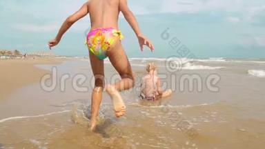 两个快乐的小女孩正在享受大海。 浪来岸边，欢度小儿女..
